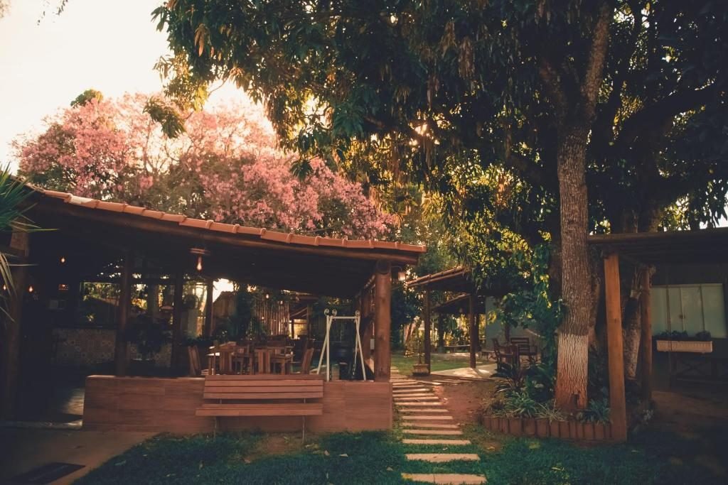 Jardim com caminho de pedras, área coberta com mesas e árvores grandes
